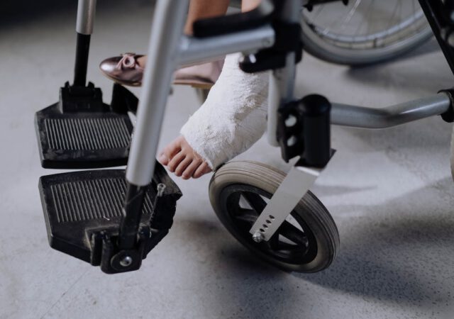 Een persoon zit in een rolstoel met een ingegipste voet.